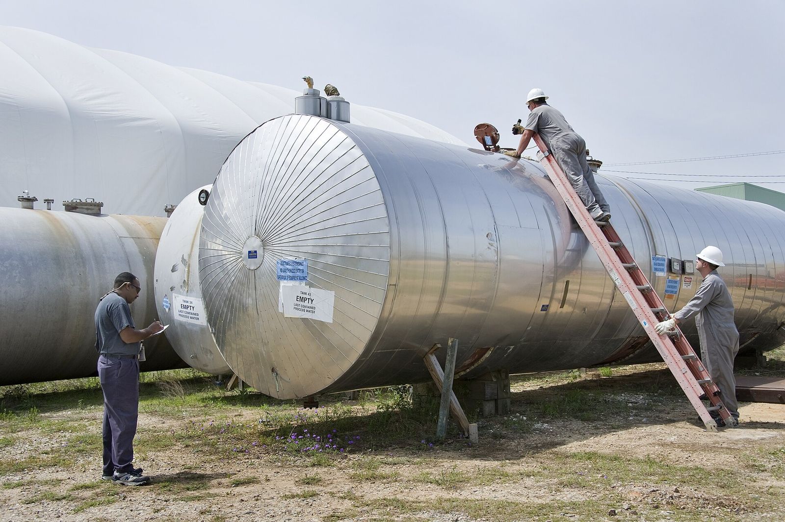 Two insulated horizontal pressure vessels on saddles, with inspectors
